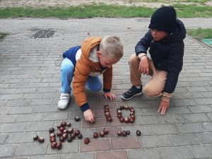 Dwóch chłopców układa kasztany na chodniku