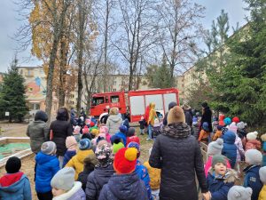 Dzieci patrzące na wjeżdżający do ogrodu przedszkolnego wóz strażacki