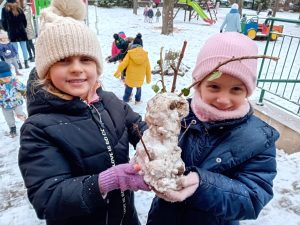 Dwie dziewczynki trzymające w dłoniach bałwana ze śniegu