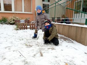 Dwóch chłopców budujących bałwanka ze śniegu.