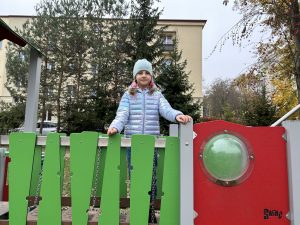 Dziewczynka na urządzeniu terenowym w ogrodzie przedszkolnym.