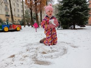 Dziewczynka lepiąca kulę śniegową.