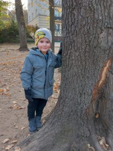 Chłopiec opierający się o pień drzewa