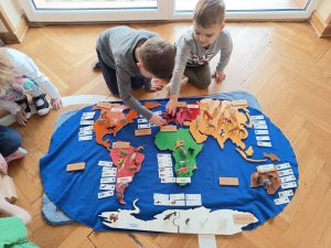 Chłopcy rozmieszczają zwierzęta na kontynentach