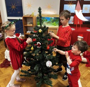 Dzieci ozdabiają choinkę.