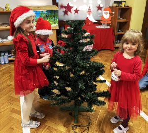 Dzieci ubierają zieloną choinkę..