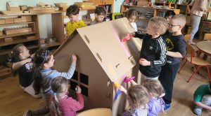3 Dzieci kolorują kartonowy domek