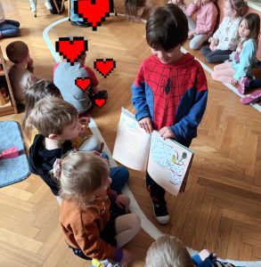 Lewek pokazuje dzieciom ilustracje w książce